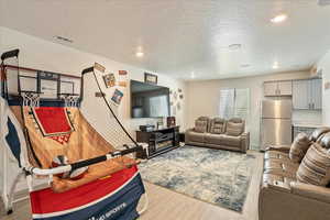 Living room with wood finished floors, a textured ceiling, recessed lighting, and baseboards