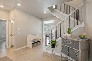 Stairway with wood finished floors, baseboards, recessed lighting, and a textured ceiling