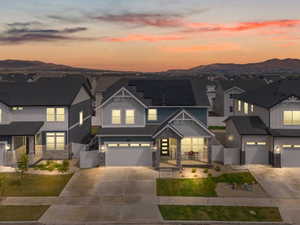 View of front facade featuring stone siding, an attached garage, a mountain view, and driveway