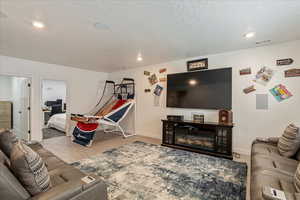 Living area featuring wood finished floors, baseboards, recessed lighting, and a textured ceiling