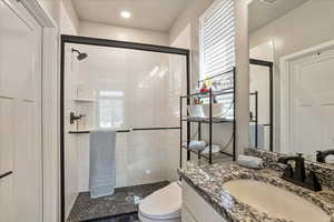 Bathroom with a shower stall, toilet, and vanity