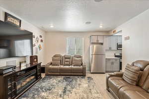 Living area featuring light wood-type flooring, a textured ceiling, and recessed lighting