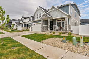 Craftsman inspired home with stone siding, a porch, concrete driveway, a garage, and a residential view