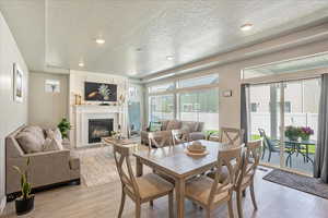 Dining room with a textured ceiling, light wood finished floors, and a large fireplace