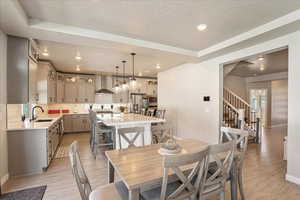 Dining area with baseboards, light wood-type flooring, a textured ceiling, recessed lighting, and stairway