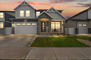 Craftsman-style house featuring stone siding, covered porch, driveway, and an attached garage