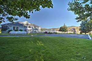 View of property's community featuring a yard, fence, a playground, and a mountain view