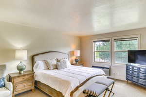 Bedroom with baseboards, carpet flooring, a wall mounted air conditioner, and a textured ceiling
