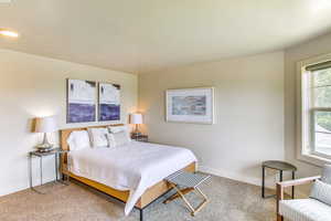 Bedroom with light colored carpet, a textured ceiling, and baseboards