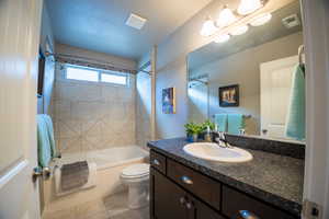 Bathroom featuring tile patterned floors, toilet,  shower combination, and vanity