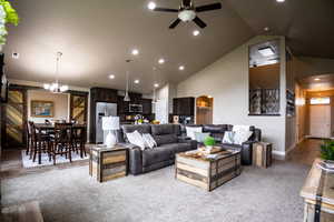 Living area featuring a barn door, ceiling fan, light carpet, high vaulted ceiling, and recessed lighting