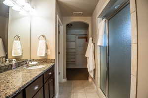 Full bathroom featuring a stall shower, tile patterned floors, vanity, a spacious closet, and baseboards