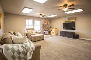 Living room with a ceiling fan, baseboards, and carpet floors