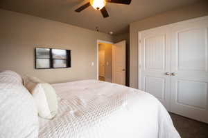 Bedroom featuring a closet, dark carpet, and ceiling fan
