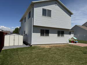 Back of property with a storage shed, a patio area, and an outbuilding