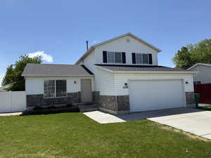 View of front of property featuring stone siding, driveway, a shingled roof, and a garage
