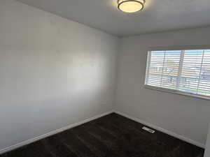 Empty room featuring baseboards, dark carpet, and a textured ceiling