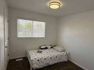 Bedroom featuring dark colored carpet and baseboards