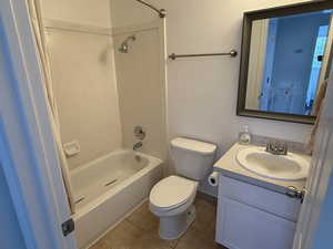 Bathroom featuring tile patterned floors, toilet, vanity, and tub / shower combination