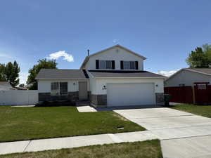 View of front of home with driveway, an attached garage, and stone siding