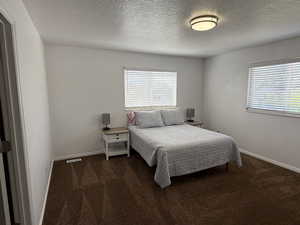 Bedroom with carpet, a textured ceiling, and baseboards