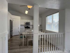 Kitchen featuring stainless steel appliances, ceiling fan, wood finished floors, backsplash, and white cabinets