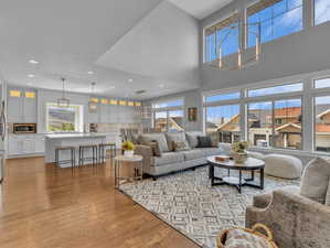 Living room featuring recessed lighting, an inviting chandelier, a high ceiling, and wood finished floors