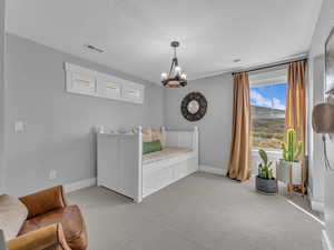 Bedroom with a rustic chandelier, and light carpet