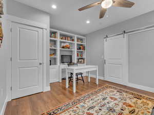 Home office with ceiling fan, a barn door, light wood-type flooring, and recessed lighting