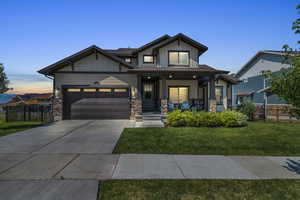 Craftsman-style home with covered porch, fence, driveway, a front yard, and an attached garage