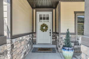 View of front entry featuring a porch and stone siding