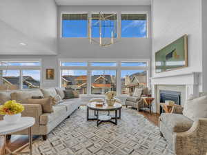 Living room with a towering ceiling, a gas enclosed fireplace, a notable chandelier, and wood flooring
