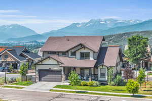 View of front facade featuring fence, a shingled roof, a mountain view, and concrete driveway