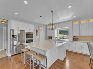 Kitchen with a notable chandelier, white cabinets, stainless steel appliances, and tasteful backsplash