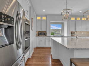 Kitchen with a beautiful view at the range, a chandelier, decorative backsplash, glass insert cabinets, and appliances with stainless steel finishes