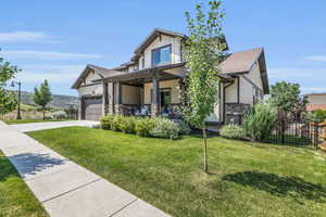 Craftsman house with concrete driveway, board and batten siding, stone siding, covered porch, and fence