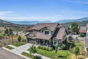 View of front of house featuring a mountain view, roof with shingles, fence, and stone siding