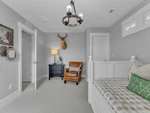 Bedroom with an inviting chandelier, light carpet and a sitting area