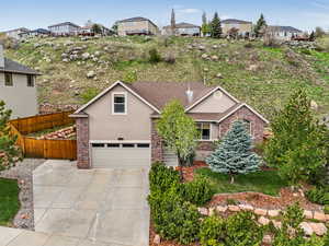 View of front of home with fence, brick siding, an attached garage, driveway, and stucco siding