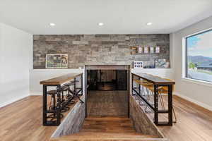 Bar featuring wood finished floors, a multi sided fireplace, baseboards, and recessed lighting