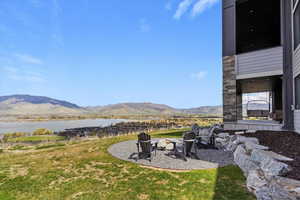 View of grassy yard featuring a fire pit and a water and mountain view
