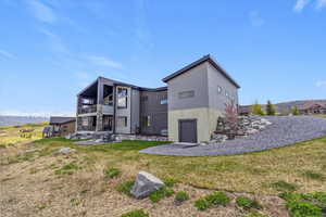 Back of house with a balcony, a lawn, and a patio area