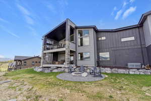 Rear view of house with a balcony, a fire pit, a patio, and a lawn