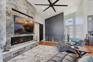 Living area with a high ceiling, wood finished floors, a fireplace, recessed lighting, and ceiling fan