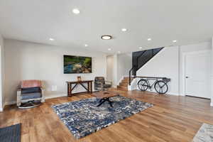 Sitting room with stairway, wood finished floors, baseboards, and recessed lighting