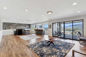 Living area with wood finished floors, recessed lighting, a textured ceiling, a water view, and baseboards