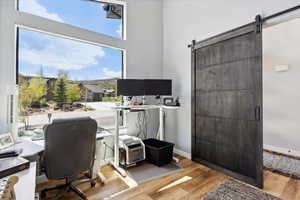 Office space featuring a barn door, wood finished floors, and baseboards