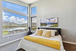 Carpeted bedroom featuring multiple windows, a water and mountain view, and baseboards