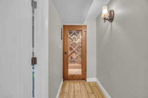 Doorway with light wood-type flooring, baseboards, and a textured ceiling