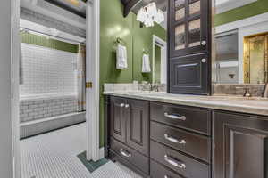 Bathroom with tile patterned floors, double vanity, and tiled shower / bath combo